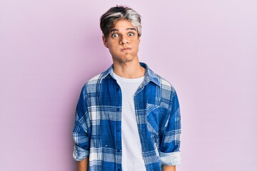 Young hispanic man wearing casual clothes puffing cheeks with funny face. mouth inflated with air, crazy expression.