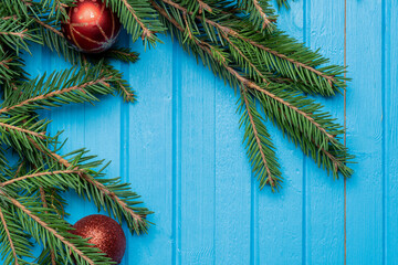 Fir, spruce branches and Christmas tree toys on blue wooden background with copy space