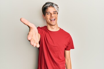 Young hispanic man wearing casual clothes smiling cheerful offering palm hand giving assistance and acceptance.