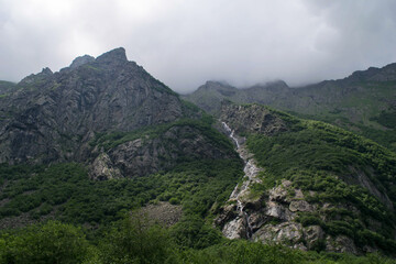 Midagrabindon  waterfalls in the gorge. Mountains in the North Caucasus in summer. Mountain tops in the clouds.