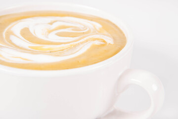 Pumpkin soup decorated with cream in a bowl on a white background