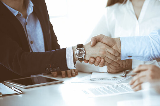 Business people shaking hands at meeting or negotiation, close-up. Group of unknown businessmen and women in modern office. Teamwork, partnership and handshake concept, toned picture