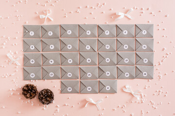 Ready-made advent calendar from gray cardboard envelopes on a table in Christmas decorations. Top...