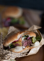 Closeup view of a bitten and tasty homemade burger covered with a burger paper.