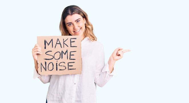 Young caucasian woman holding make some noise banner smiling happy pointing with hand and finger to the side