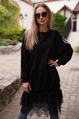 Young blond-haired fashion model takes photos for a fashion store outdoors with a blurred background.