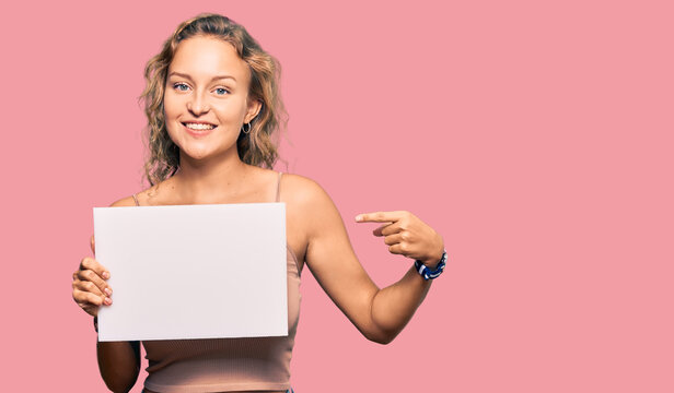 Beautiful caucasian woman holding blank empty banner smiling happy pointing with hand and finger