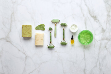 Cosmetic skin care products, jade stone face massager, creams, gel and oil. Roller massage of the face. Flat lay, top view