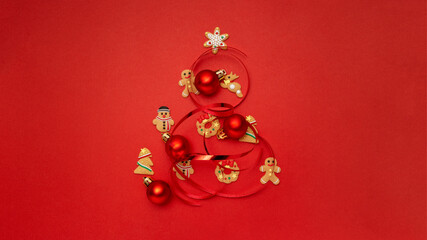 Christmas tree made with Christmas cookies and Christmas balls on red background