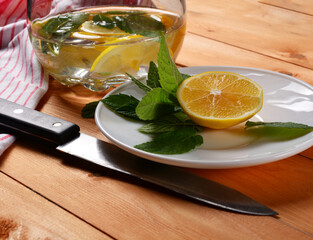 preparation of lemonade, a decanter of water with mint and lemon slices, lemon and fresh mint on a...