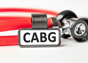 CABG Coronary artery bypass graft lettering on a business card with a holder, next to the red...