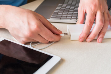 Power bank charges tablet on desk. Universal external battery for gadgets. Power bank for charging...