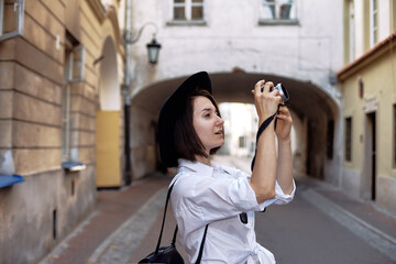 Obraz premium The girl in the black hat shooting in an old european town.
