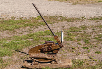 Riesco Island, Chile - December 12, 2008: Posada Estancia Rio Verde working farm. Large heavy manual cable cutter mounted on wooden beam and se on dry grassland.