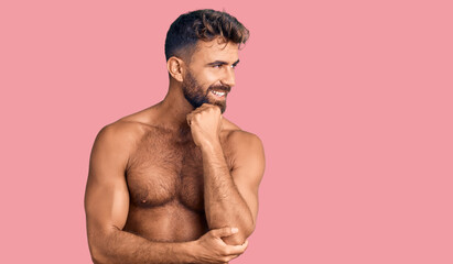 Fototapeta premium Young hispanic man wearing swimwear shirtless with hand on chin thinking about question, pensive expression. smiling with thoughtful face. doubt concept.