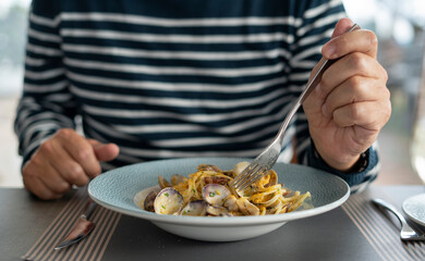 detail male hand eating pasta spaghetti with clams and mullet, Mediterranean food