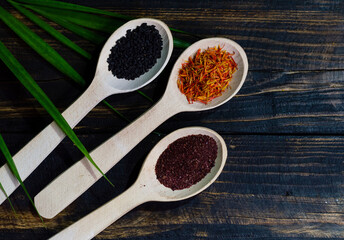 ndian spices in wooden spoons. Herbs. On a wooden burnt background in the village style, saffron, black cumin, sumac and other spices are highlighted. Culinary background with the ability to insert a 