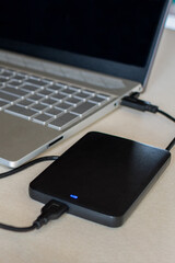 External hard drive connect to laptop computer on desk. A portable hard drive. The concept of data storage.