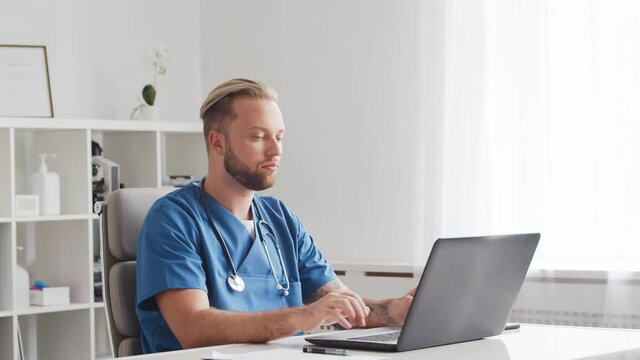Professional medical doctor is working in hospital office using computer technology.