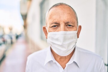 Senior man wearing medical mask standing at the city.