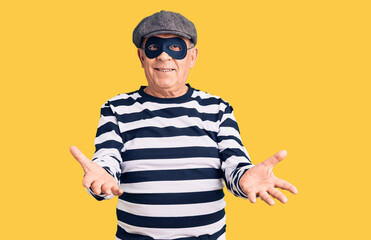 Fototapeta premium Senior handsome man wearing burglar mask and t-shirt smiling cheerful offering hands giving assistance and acceptance.