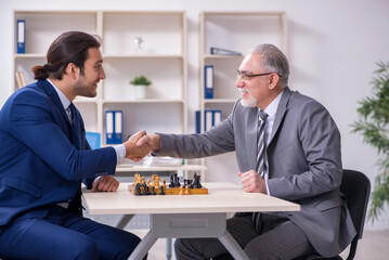 Two businessmen playing chess in the office