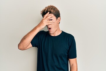Handsome caucasian man wearing casual clothes peeking in shock covering face and eyes with hand,...