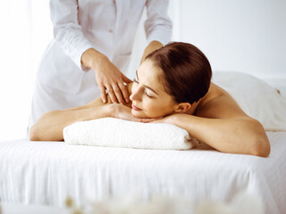 Fototapeta na wymiar Beautiful brunette woman enjoying back massage with closed eyes. Spa and medicine concept