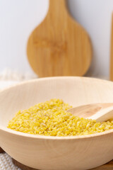Raw bulgur in wooden bowl, close up shot. Healthy dietary vegan gluten free product. vertical photo