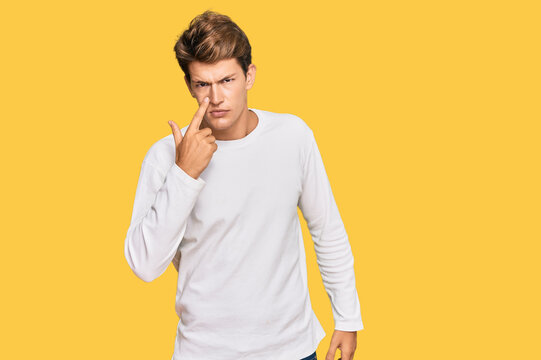 Handsome caucasian man wearing casual white sweater pointing to the eye watching you gesture, suspicious expression