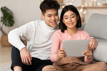 Japanese Couple Using Tablet Watching Movie Online Sitting At Home
