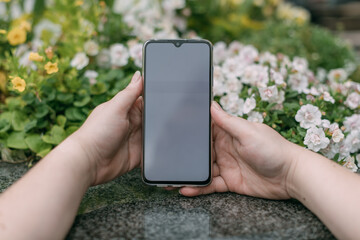 Mobile phone in female hands on a background of granite and flowers