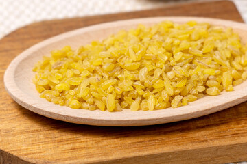 bulgur in a wooden bowl on wooden table, rustic style. Bulgur wheat grains