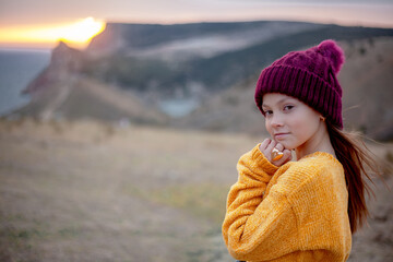 Back view of hipster woman traveler wearing knitted sweater, ring heart, hat  walking  on top of the mountain landscape and looking to the sea