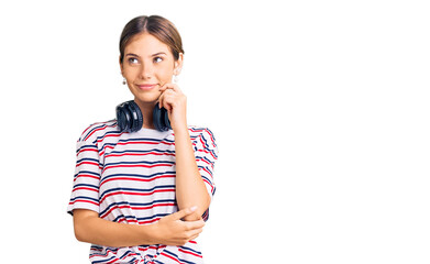 Beautiful caucasian woman with blonde hair wearing gym clothes and using headphones serious face...