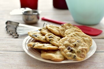 Freshly made homemade chocolate chip cookies warm from oven ready to eat with baking equipment background