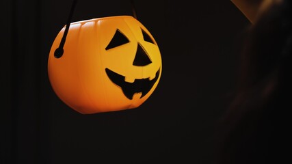 Close-up - the head of an orange glowing pumpkin with a carved smile, which the girl turns in front of her. Holiday attribute and symbol. Halloween Eve. October holiday.