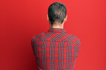 Handsome caucasian man wearing casual red tshirt standing backwards looking away with crossed arms