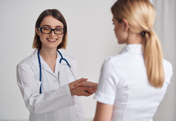 Fototapeta premium doctor and patient shaking hands on a light background stethoscope around the neck