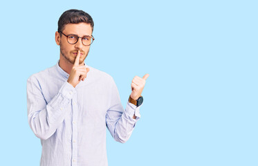Handsome young man with bear wearing elegant business shirt and glasses asking to be quiet with finger on lips pointing with hand to the side. silence and secret concept.