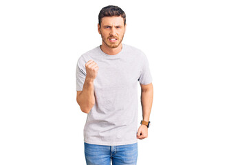 Handsome young man with bear wearing casual tshirt angry and mad raising fist frustrated and furious while shouting with anger. rage and aggressive concept.