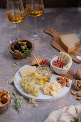 Assorted cheeses on marble plate with figs, nuts, grapes and honey
