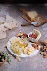 Assorted cheeses on marble board with figs, nuts, grapes and honey