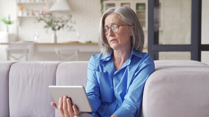 Senior old grey-haired woman grandmother holding digital tablet video conference calling talking with doctor or family during social distance virtual visit in online telemedicine chat meeting at home.