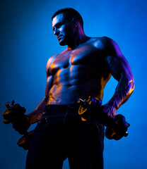 Fototapeta na wymiar Muscular man exercises with dumbbells on neon light.