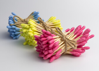 Wooden cotton ear swabs or sticks connected with rope on white background. Colourful happy lifestyle, trends in everyday routine, isolated, close-up.