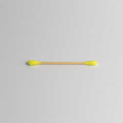 One wooden yellow cotton ear swab or stick on white background. Recycling and sustainability problem in everyday reasonable consumption. isolated, close-up.