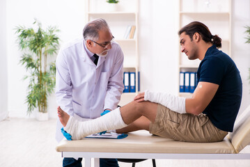 Young injured man visiting old doctor traumatologist