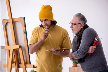 Old man taking lesson from young painter