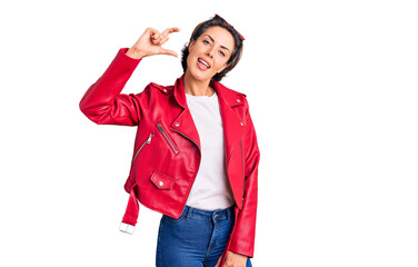 Obraz premium Young beautiful woman wearing red leather jacket smiling and confident gesturing with hand doing small size sign with fingers looking and the camera. measure concept.